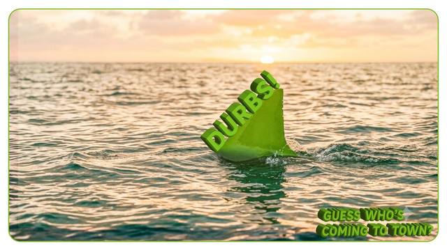 A green triangular fin shaped like the Leroy Merlin logo breaking the ocean surface at sunset